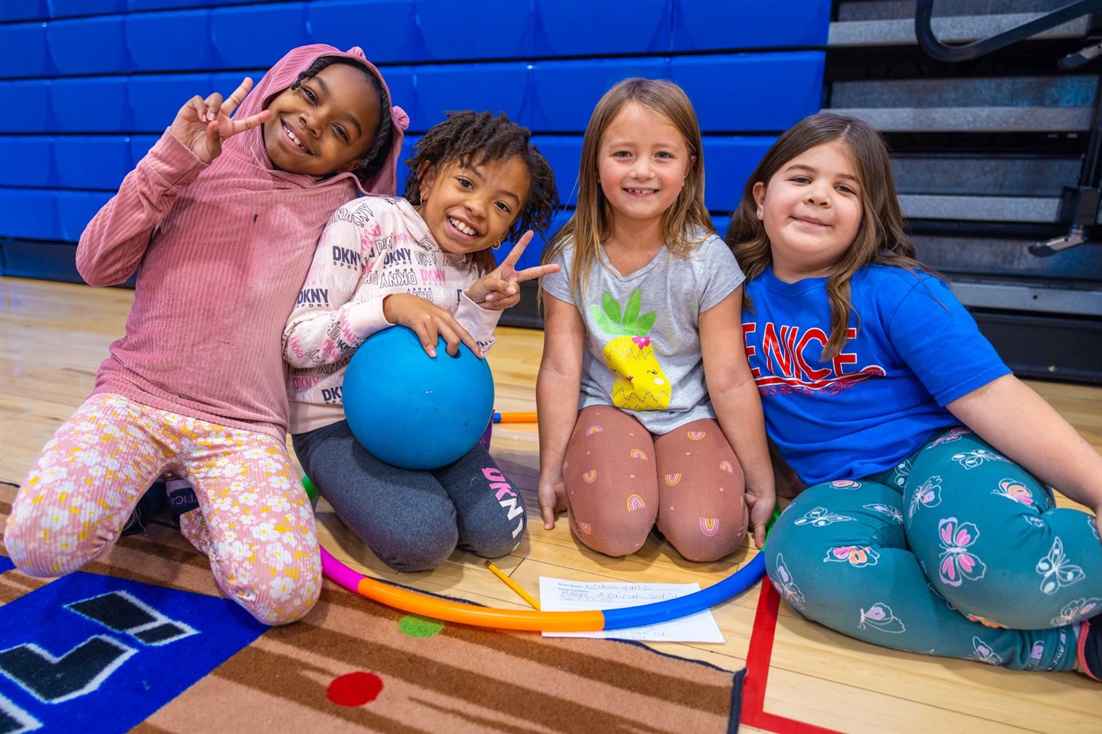four girls smiling with peace signs and a bowling ball